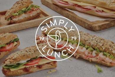 Simply Lunch Audio Case Study A delightful array of assorted sandwiches with various fillings is laid out across the table, prominently displaying the Simply Lunch logo at its centre.