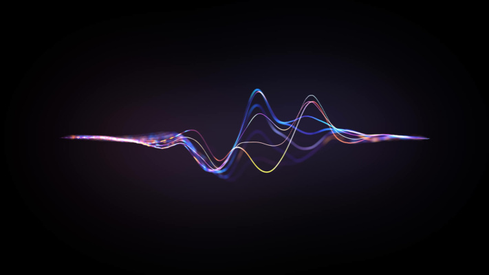 blog-audio-wave Colourful, wavy lines resembling a digital sound wave or frequency spectrum appear against a dark background, with gradients of blue, purple and yellow light.