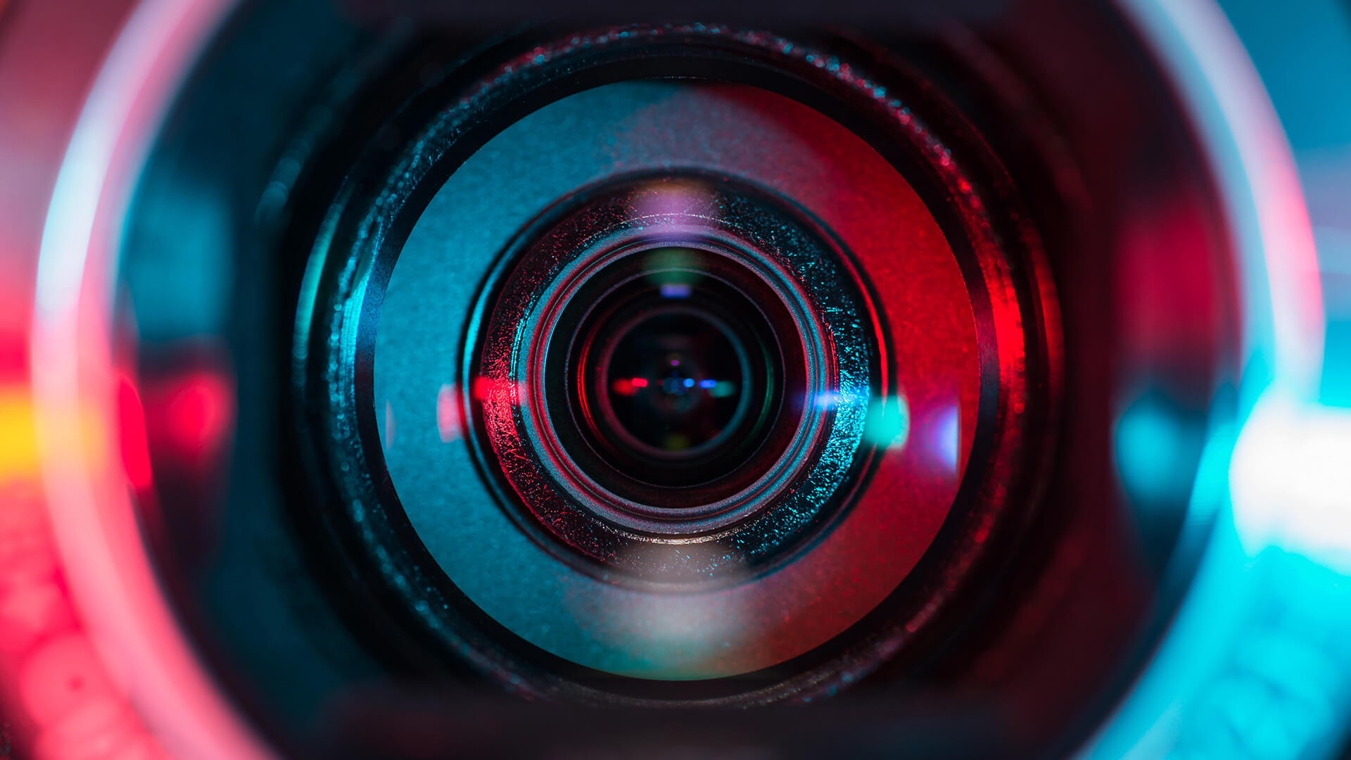 Close-up of a camera lens reflecting blue and red light, ideal for producing instructional explainer videos.