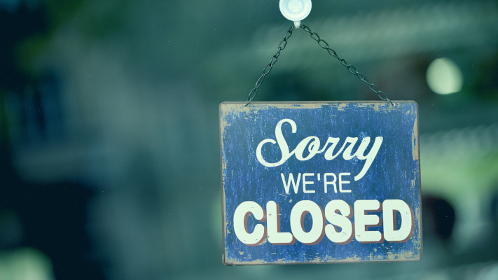 blog-ooh A blue and white sign hanging on a glass door reads Sorry We’re Closed.
