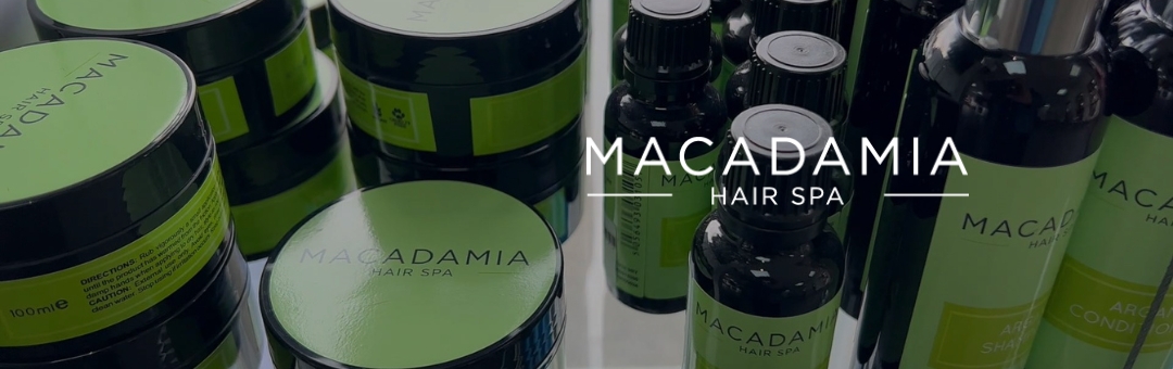 A collection of Macadamia Hair Spa hair care products with green labels, including jars and bottles, is displayed on a surface.