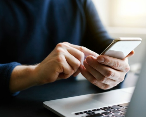 Man with a finger on the screen using a mobile phone in the office