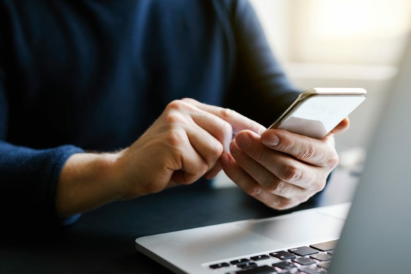 A person is using a smartphone with a laptop in the foreground, enjoying seamless connectivity and reliable phone lines for uninterrupted communication.