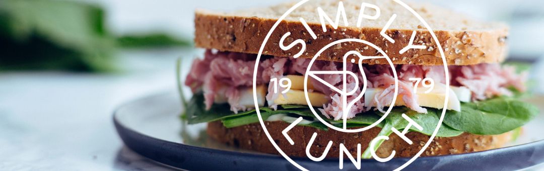 A close-up of a ham sandwich with spinach and cheese on wholemeal bread. The words Simply Lunch and 1979 are overlaid in a circle.