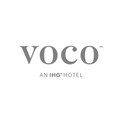 Logo of voco, an IHG Hotel, in grey text on a transparent background.